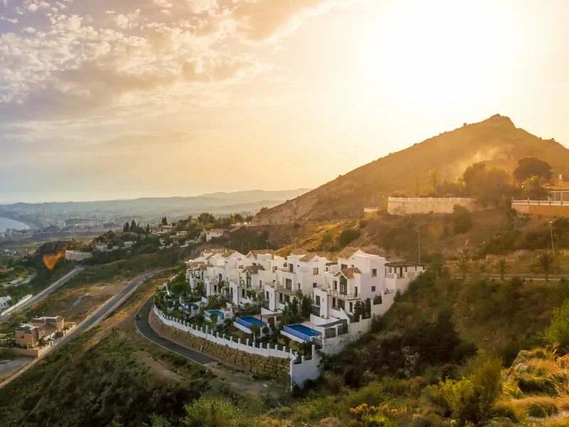 White villas on a hillside above the coast in the low evening sun
