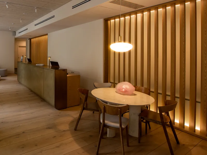 A quiet lobby with a reception desk, two laptops and a round table under a warm pendant light