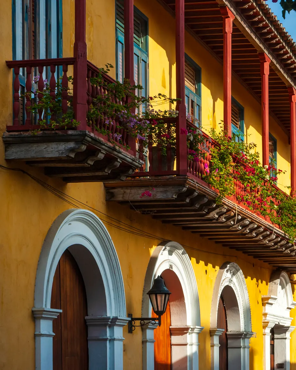 Colonial street with flowering wooden balconies above arched doorways