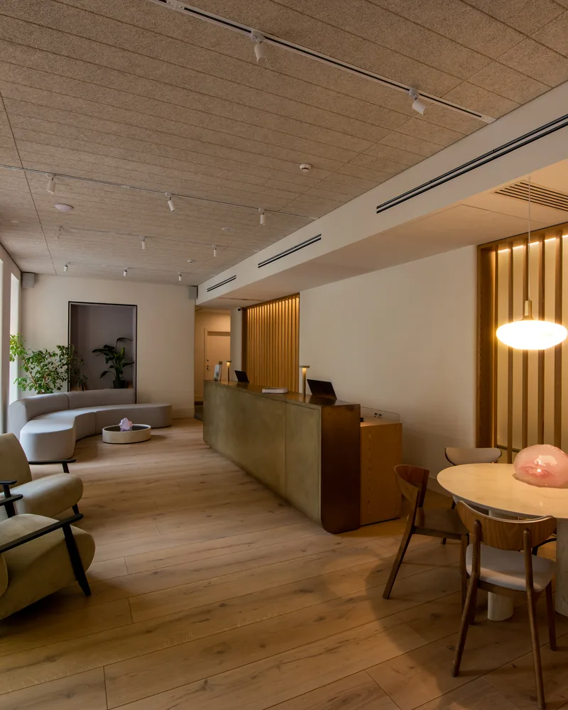 Hotel lobby in warm evening light, lounge chairs by the window and a reception desk under a glowing pendant