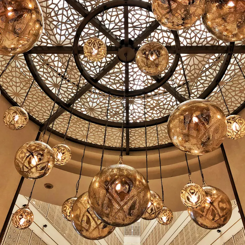 Brass pendant lights hanging beneath a carved lattice dome