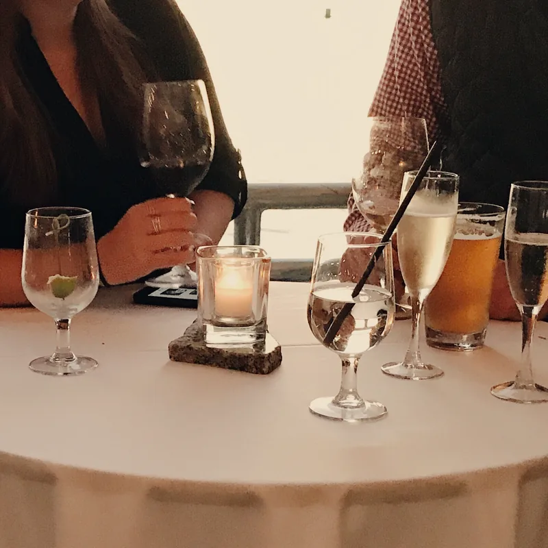 Guests with wine and champagne around a candlelit high table by the water