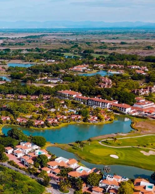 Aerial view of a golf course and lagoons among villas near the coast