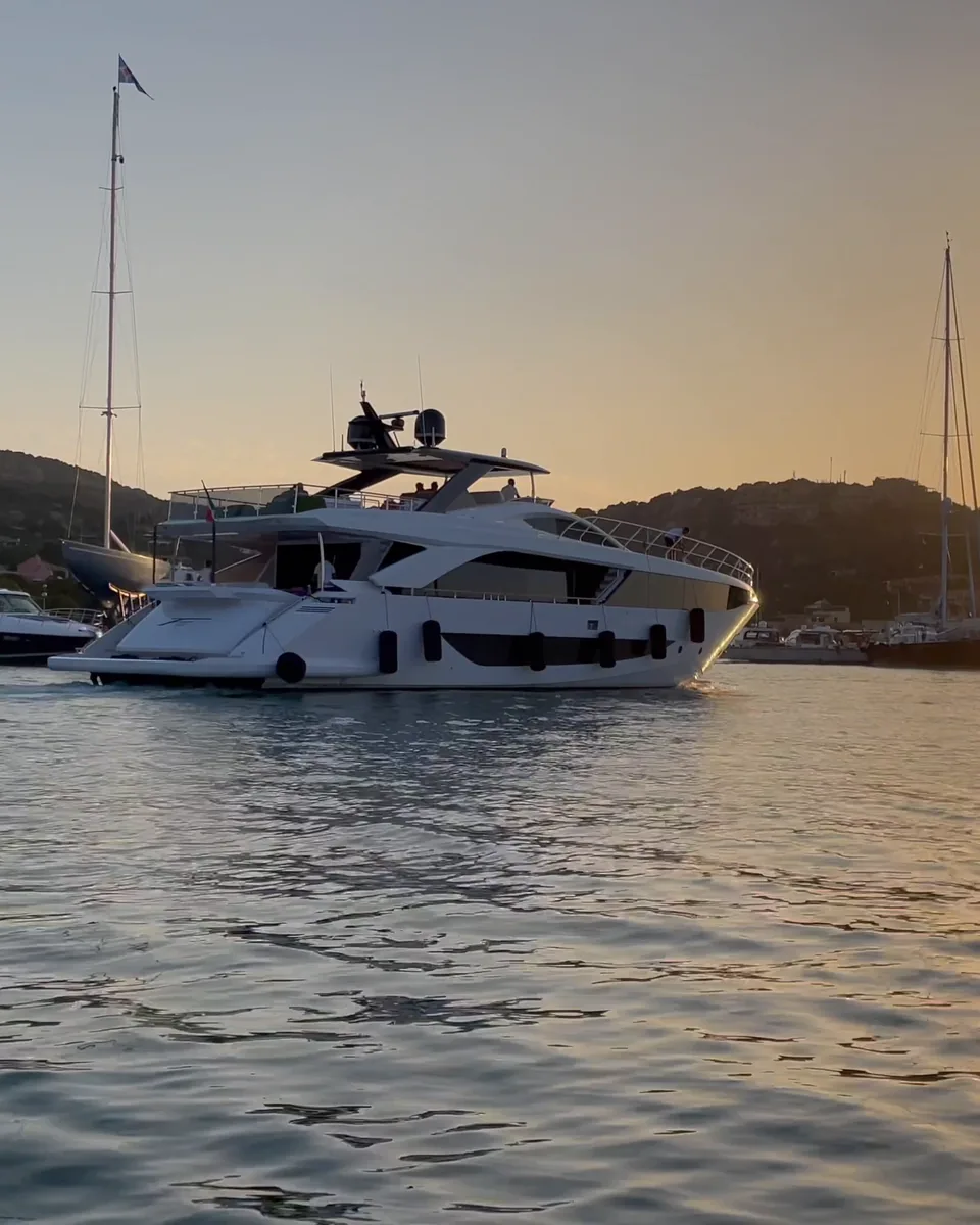 A motor yacht at anchor in a harbour at sunset