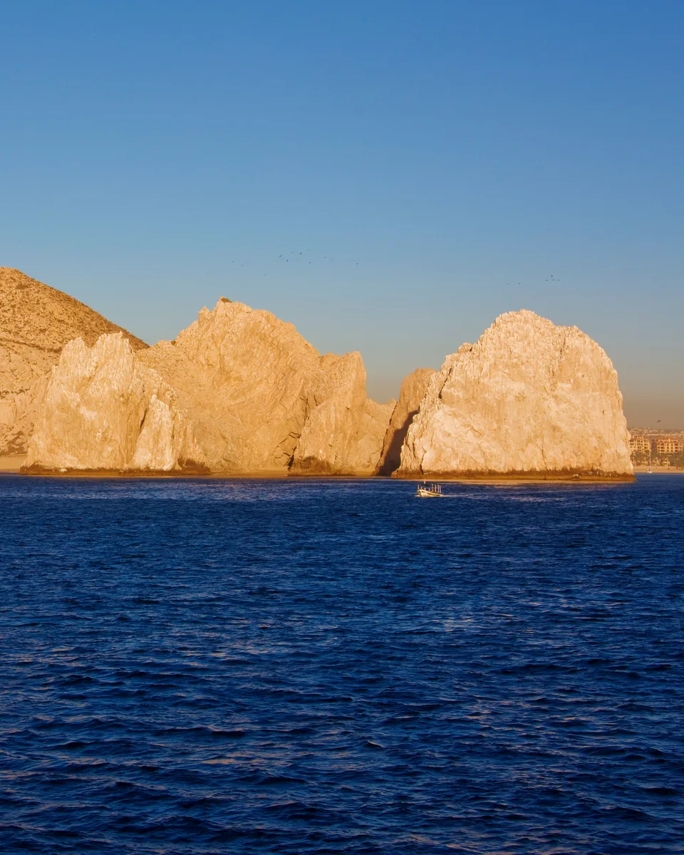 Rock arches rising from deep blue water in late sun