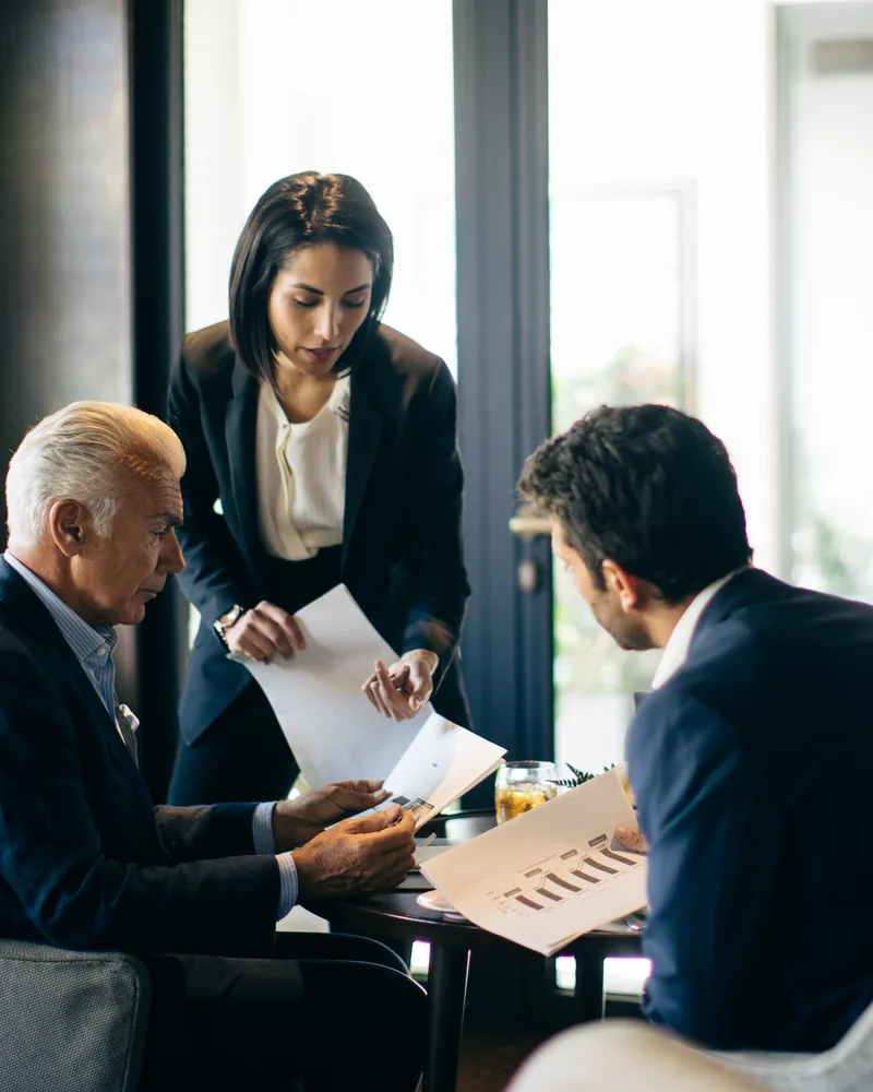 Three executives reviewing papers together at a lounge table