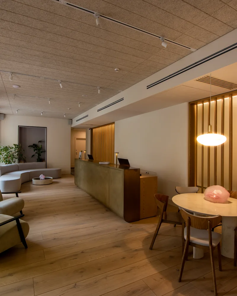 A hotel lobby with a reception desk, lounge seating and a warm pendant light