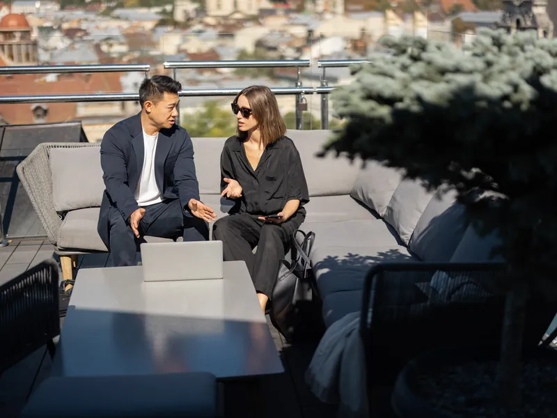 Two colleagues in conversation on a rooftop terrace above a city