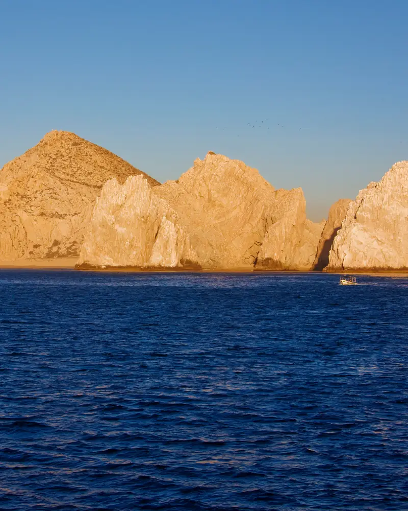 Golden sea cliffs seen from the water in the last light of the day