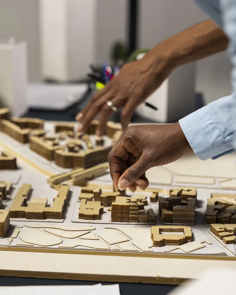Hands arranging blocks on a white architectural massing model