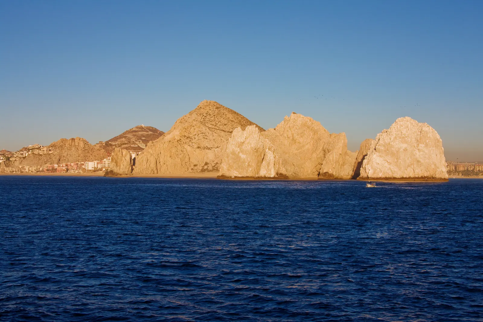 Sandstone sea arches rising from deep blue water at golden hour