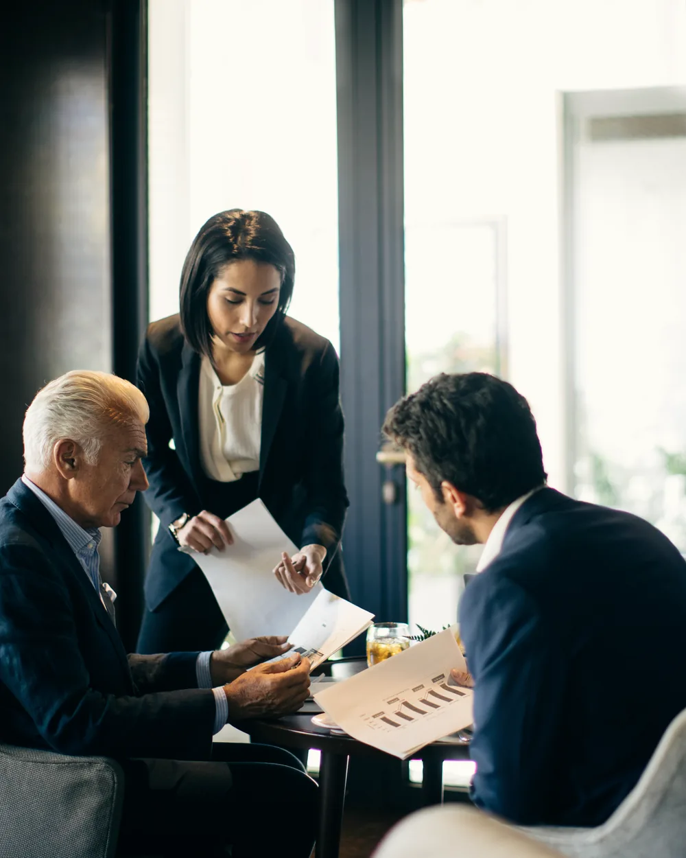 Three colleagues reviewing documents together at a lounge table