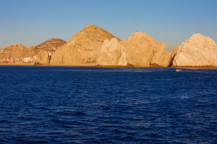 Sea arches of golden rock rising from deep blue water in late sun
