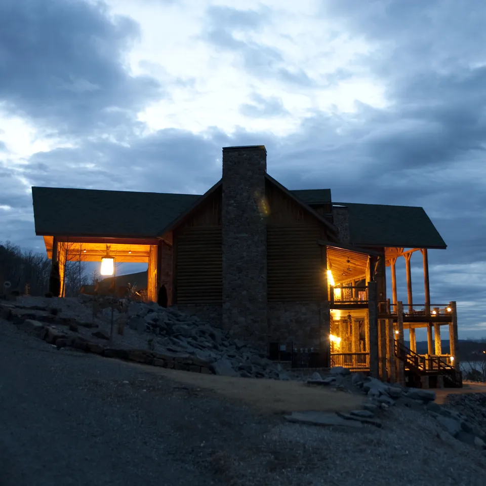 The lit porch of a timber lodge at dusk
