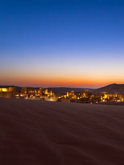 The lights of a desert retreat among the dunes after sunset