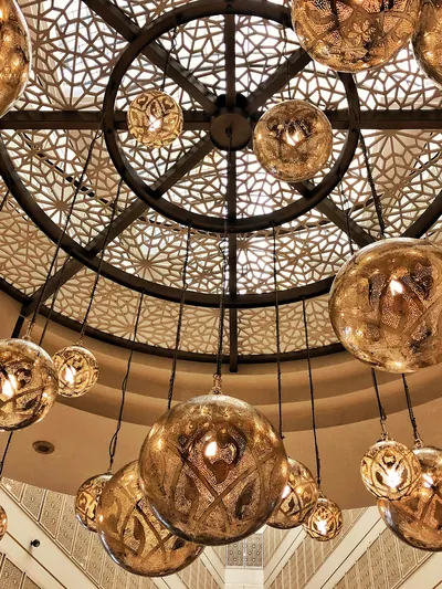 Brass lanterns glowing under a carved lattice dome