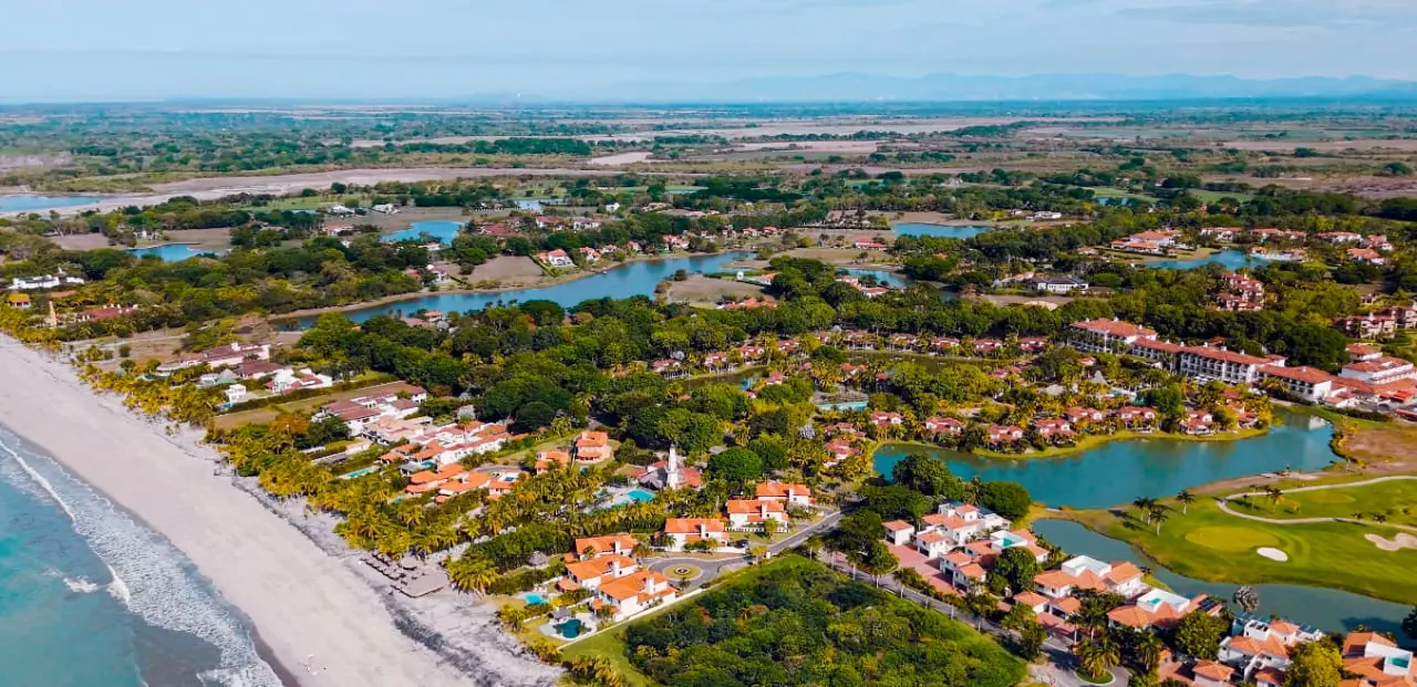 Golf fairways and a lagoon among tiled villas near the beach, seen from the air