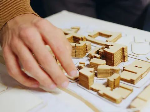 An architect’s hand on a wooden master-plan model