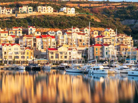 A harbour village and moored boats reflected in calm water at dawn