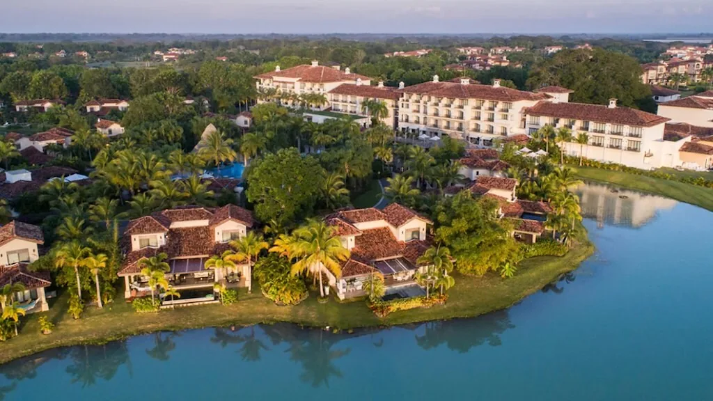 Aerial view of tile-roofed homes among palms along a lagoon in Buenaventura, in warm low sunlight