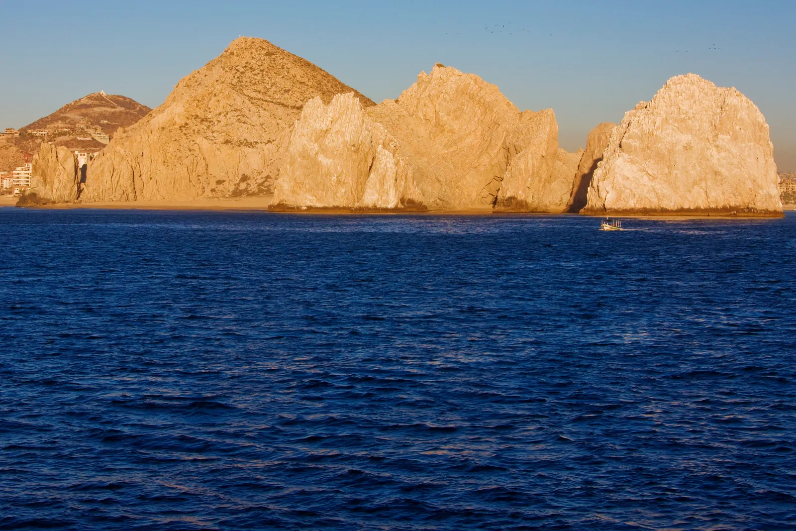 Golden granite headlands above a deep blue sea in late-afternoon light