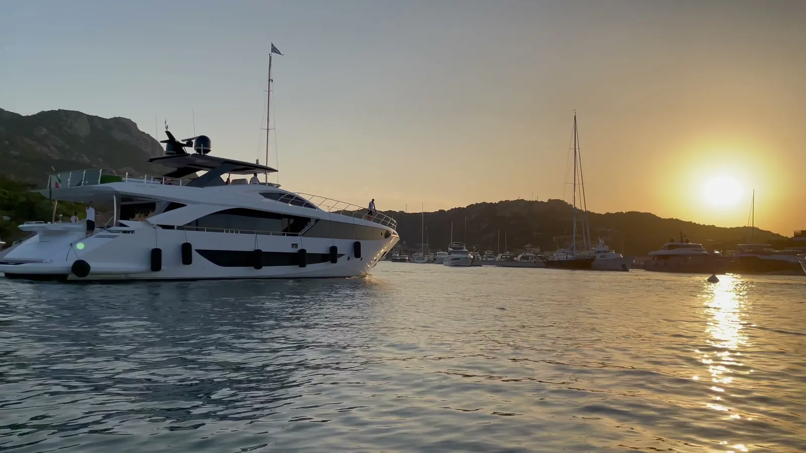 Marina at golden hour with yachts moored below a waterfront development