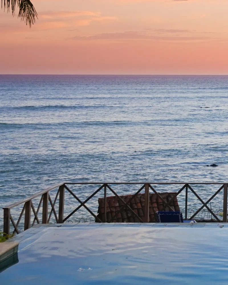 An infinity pool and terrace overlooking the Pacific at sunset