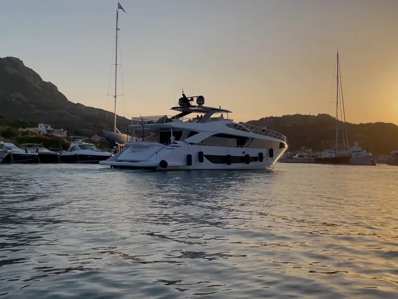 A motor yacht crossing a marina at sunset