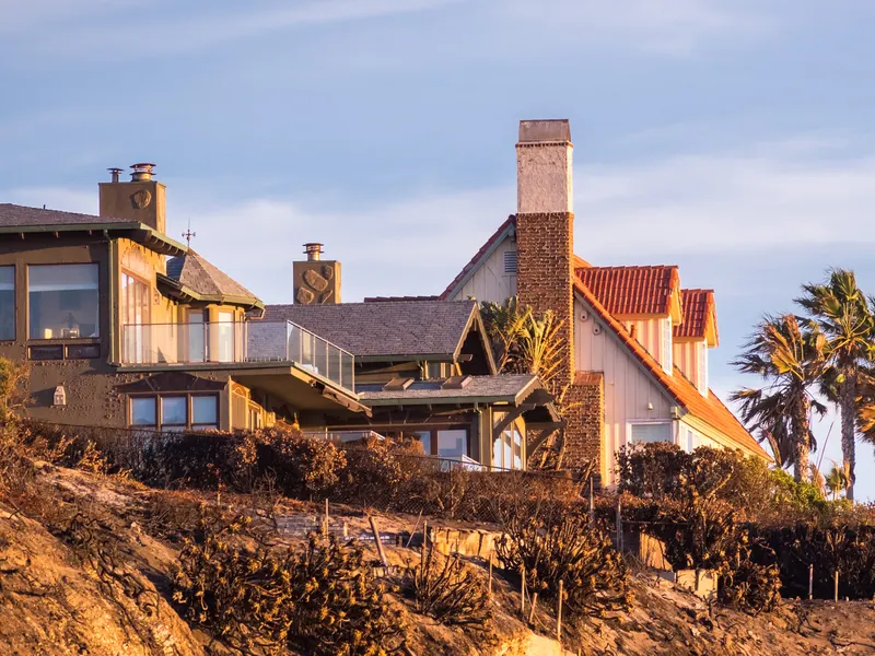 Clifftop houses and palms catching the last sun above the sea